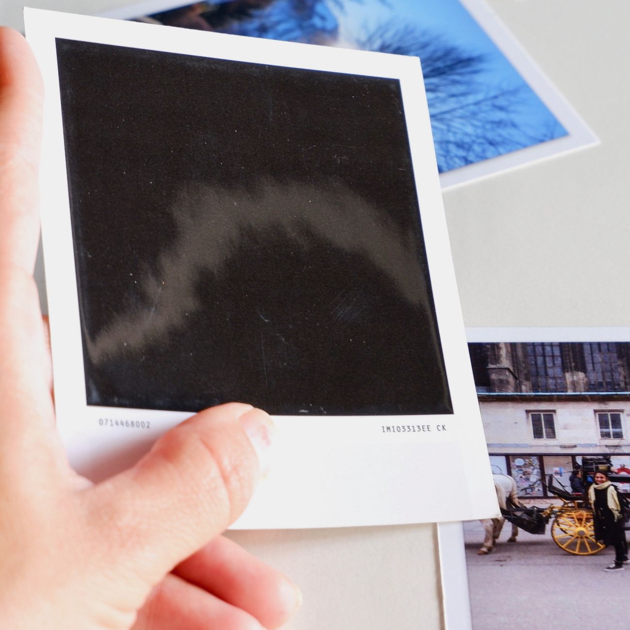 holding set of polaroid prints